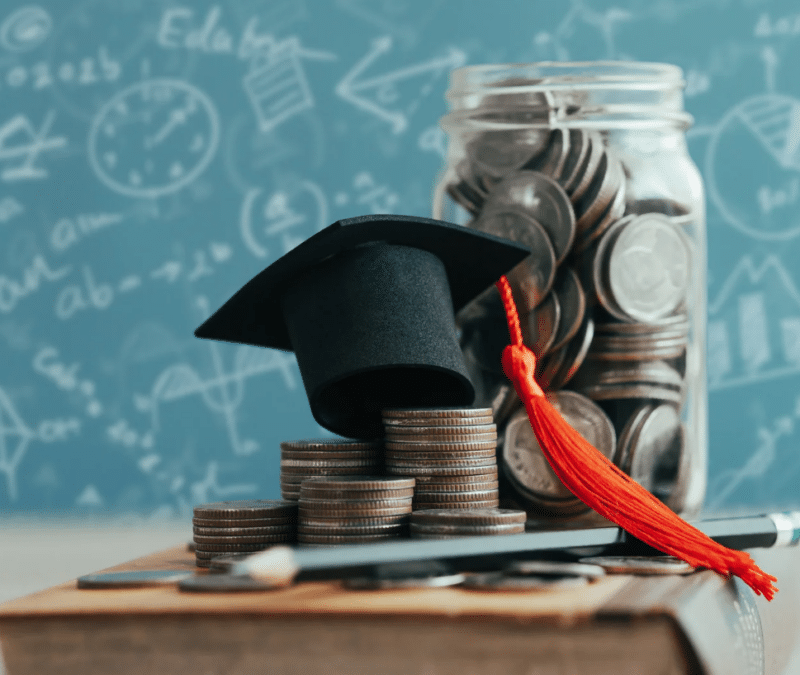 Graduation cap and a glass jar full of coins, blackboard in the background